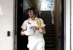 a man in white uniform holding a yellow bat and wearing a green helmet while walking up some stairs