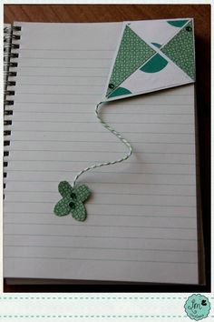 an open notebook with a string attached to the cover and a paper butterfly on it