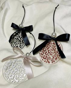 two ornaments with bows are on a white sheet and one has a leopard print ornament