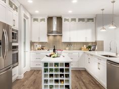 a large kitchen with white cabinets and stainless steel appliances, including a wine rack on the island