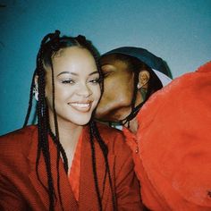 a man kissing a woman on the cheek while she is dressed in an orange outfit