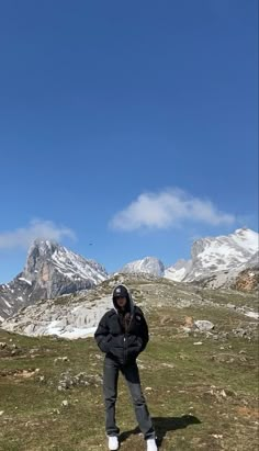 a man standing on top of a grass covered hillside