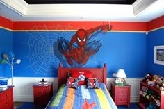 a child's bedroom decorated in red, blue and yellow with a spiderman mural