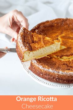 someone cutting into a cake with orange ricotta cheesecake on the top and bottom