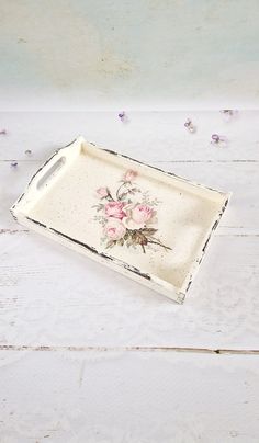 an old tray with flowers painted on it sitting on a white wooden table next to purple flowers