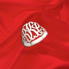 a silver ring with the word monogram on it sitting on a red satin background