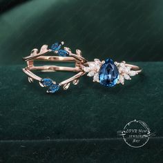 two rings with blue and white stones sitting on top of a green velvet covered surface