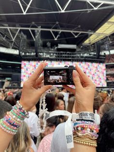 a person holding up a cell phone in front of a crowd at a music festival