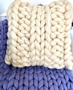 a knitted pillow sitting on top of a blue blanket