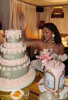 a woman in a wedding dress standing next to a three tiered cake with flowers on it