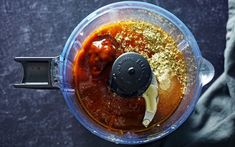 an overhead view of a food processor filled with meat and seasoning, on a dark surface