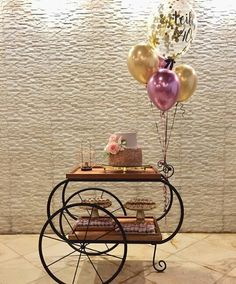 a table topped with balloons and cake on top of a wooden table next to a wall