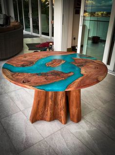 a table made out of wood with blue paint on the top and bottom, sitting in front of a glass door