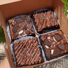 four cookies and oreo cookie squares in a box with chocolate frosting on them