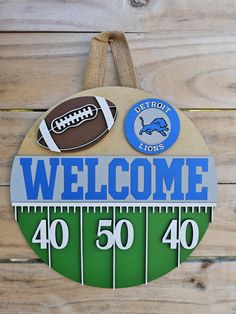 a welcome sign for the detroit lions with footballs and numbers on it, hanging from a wooden wall