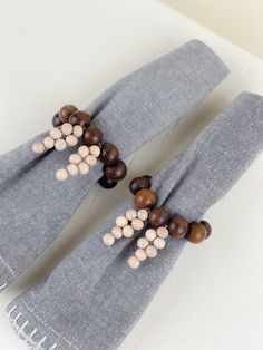 two gray scarfs with brown and white beads on them