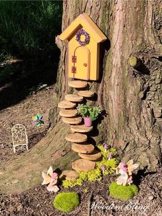 a birdhouse made out of rocks and stones sitting on the ground next to a tree