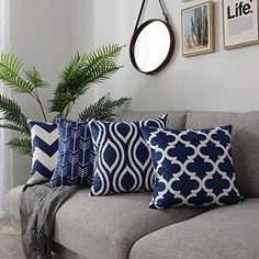 a gray couch with blue and white pillows sitting on top of it next to a potted plant