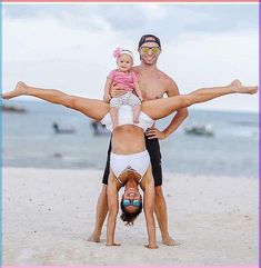 a man and woman doing handstand on the beach with a baby girl in her arms