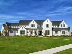 a large white house sitting on top of a lush green field under a blue sky