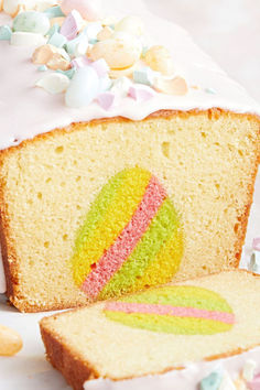 a slice of cake with white frosting and colorful icing on the top is next to a piece of bread