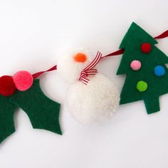 two felt christmas trees with pom - poms hanging from them