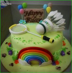 a birthday cake decorated with tennis equipment and rainbows on the top is a happy bday sign