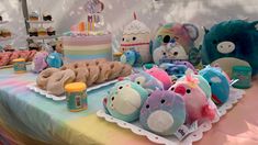 a table topped with lots of stuffed animals next to cakes and cupcakes on top of it