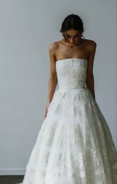 a woman in a white wedding dress standing next to a wall