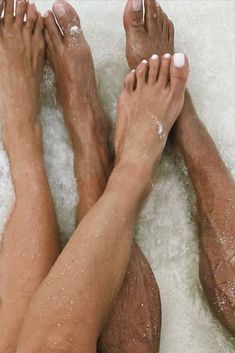 two people with their feet covered in foamy water next to each other on a bathtub