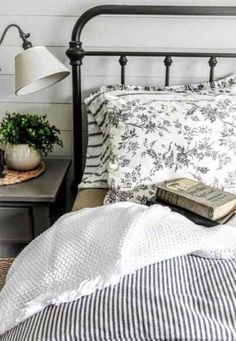 a black and white bed topped with pillows next to a night stand filled with books