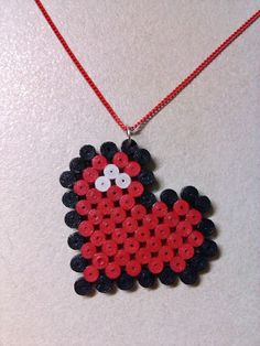 a red and black beaded animal is hanging from a necklace