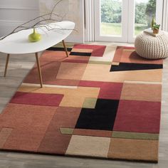 a living room area with a rug, table and vase on the floor in front of a window