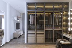 a walk in closet with mirrored doors and lights on the wall, next to a bed