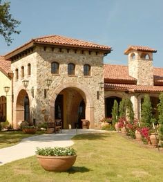 a large stone house with lots of plants in the front yard