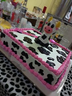 a cow cake sitting on top of a table covered in pink and black frosting