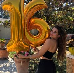 a woman holding up a large balloon shaped like the number twenty five