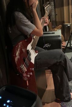 a woman sitting on top of a wooden floor next to a guitar