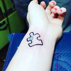 a person with a tattoo on their arm holding a piece of a jigsaw puzzle