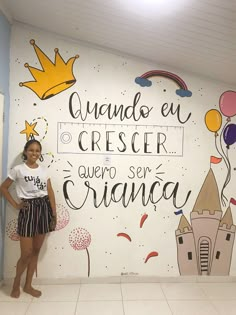 a woman standing in front of a wall painted with princess and castle images on it