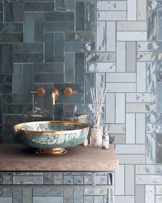 a bowl shaped sink sitting on top of a wooden counter next to a tiled wall