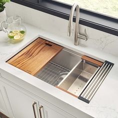 a stainless steel kitchen sink with wooden cutting board in the bottom and drainer on the side