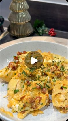 a white plate topped with ravioli covered in cheese and bacon next to a christmas tree