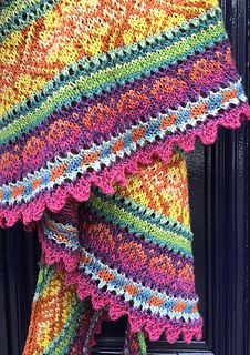 a colorful crocheted shawl hanging on a door