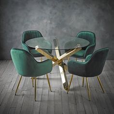 a glass dining table surrounded by green chairs and gold trimmings on a wooden floor