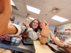 two young women are taking a selfie in the mirror while sitting at a counter