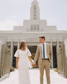 a man and woman holding hands in front of a building