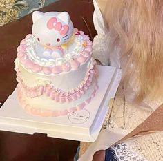 a hello kitty cake sitting on top of a white box next to a woman's face