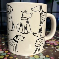 a coffee mug with dogs on it sitting on a polka dot tablecloth covered table