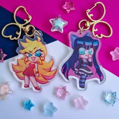 two keychains with cartoon characters on them sitting next to star shaped stars and confetti